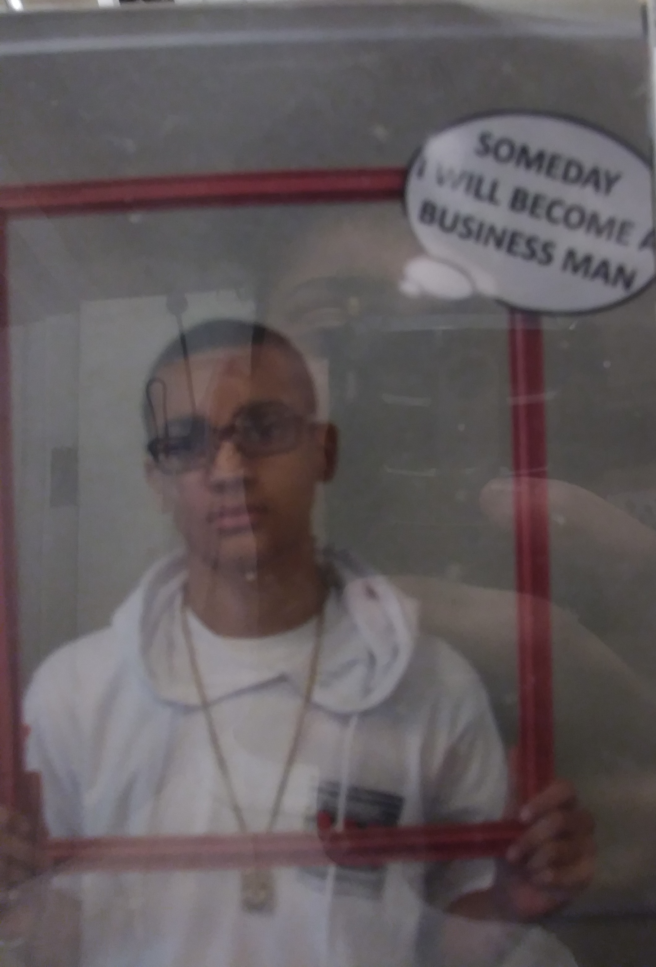 Que at age 12 on Career Day holding a sign that reads Someday I Will Become A Business Man