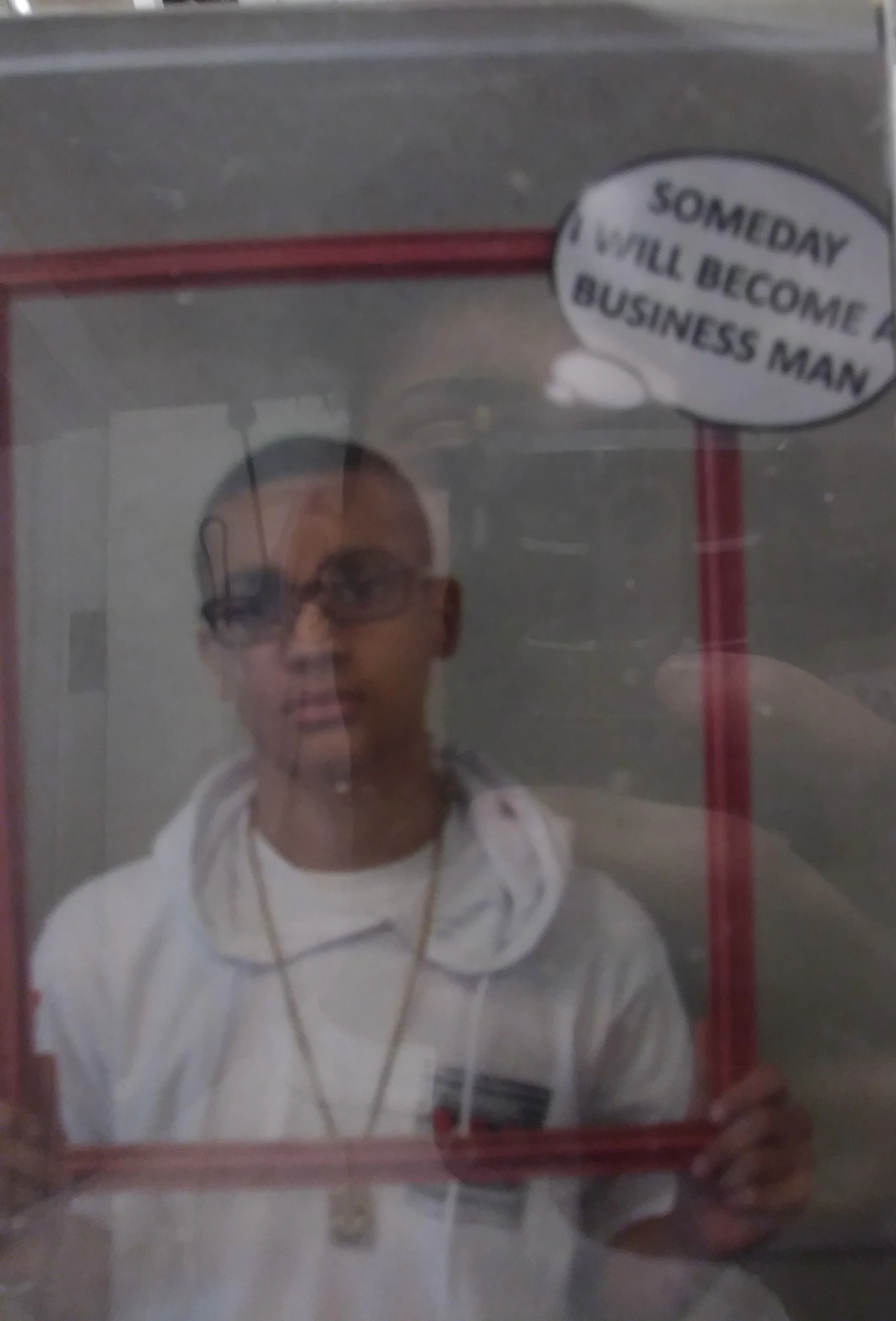 Que at age 12, Career Day, holding a sign that reads Someday I Will Become A Business Man